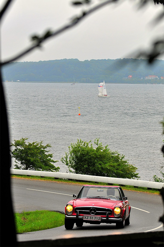 Flere steder på serpentinevejen kan tilskuerne komme tæt på biler som Pert Hjorts Mercedes 230 SL, her med Vejle Fjord i baggrunden
(Foto: Michael Eisenberg)